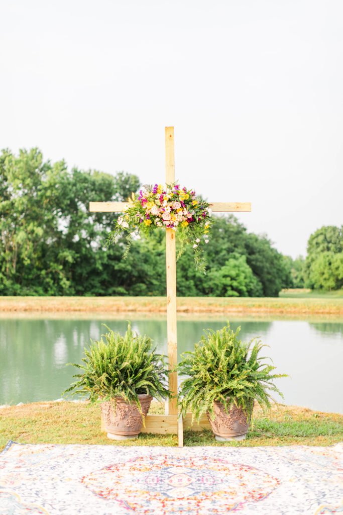 This intimate summer elopement was held on the bride's family property next to a lake with an island. They had a beautiful wooden cross decorated in bright colored flowers.