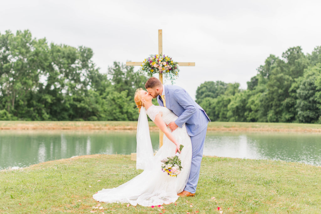 The groom dips and kisses his bride after saying "I do" at their intimate summer elopement.