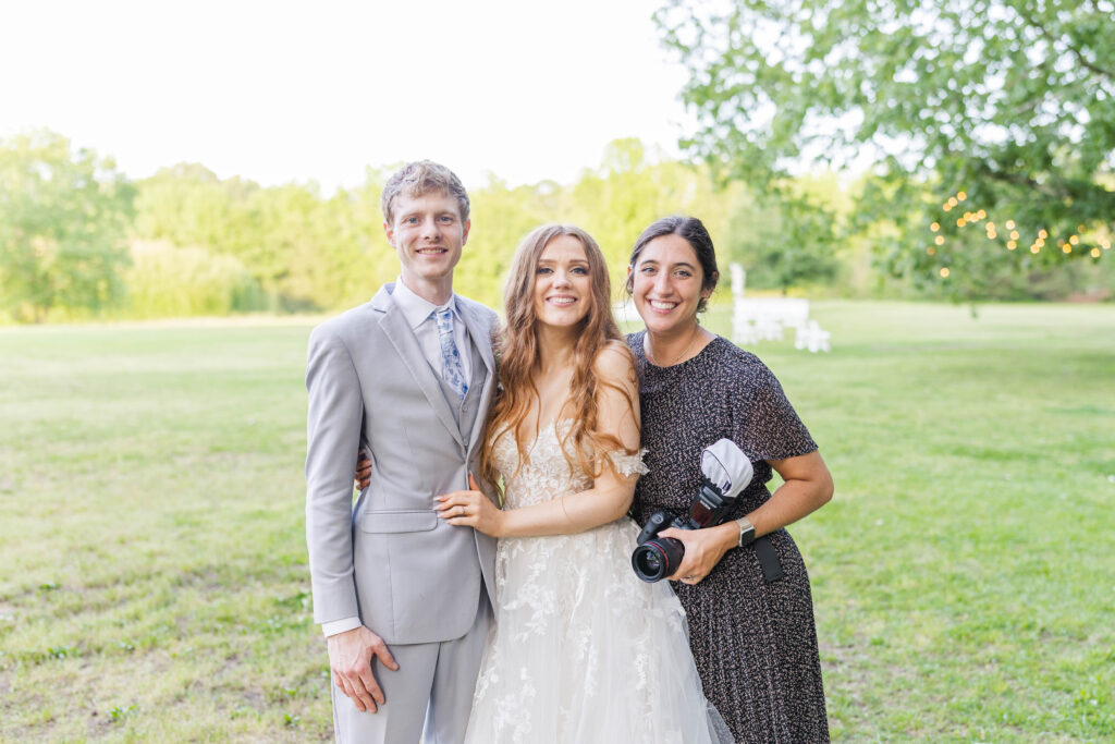 Wedding photographer taking a portrait with her bride and groom at the end of the wedding day